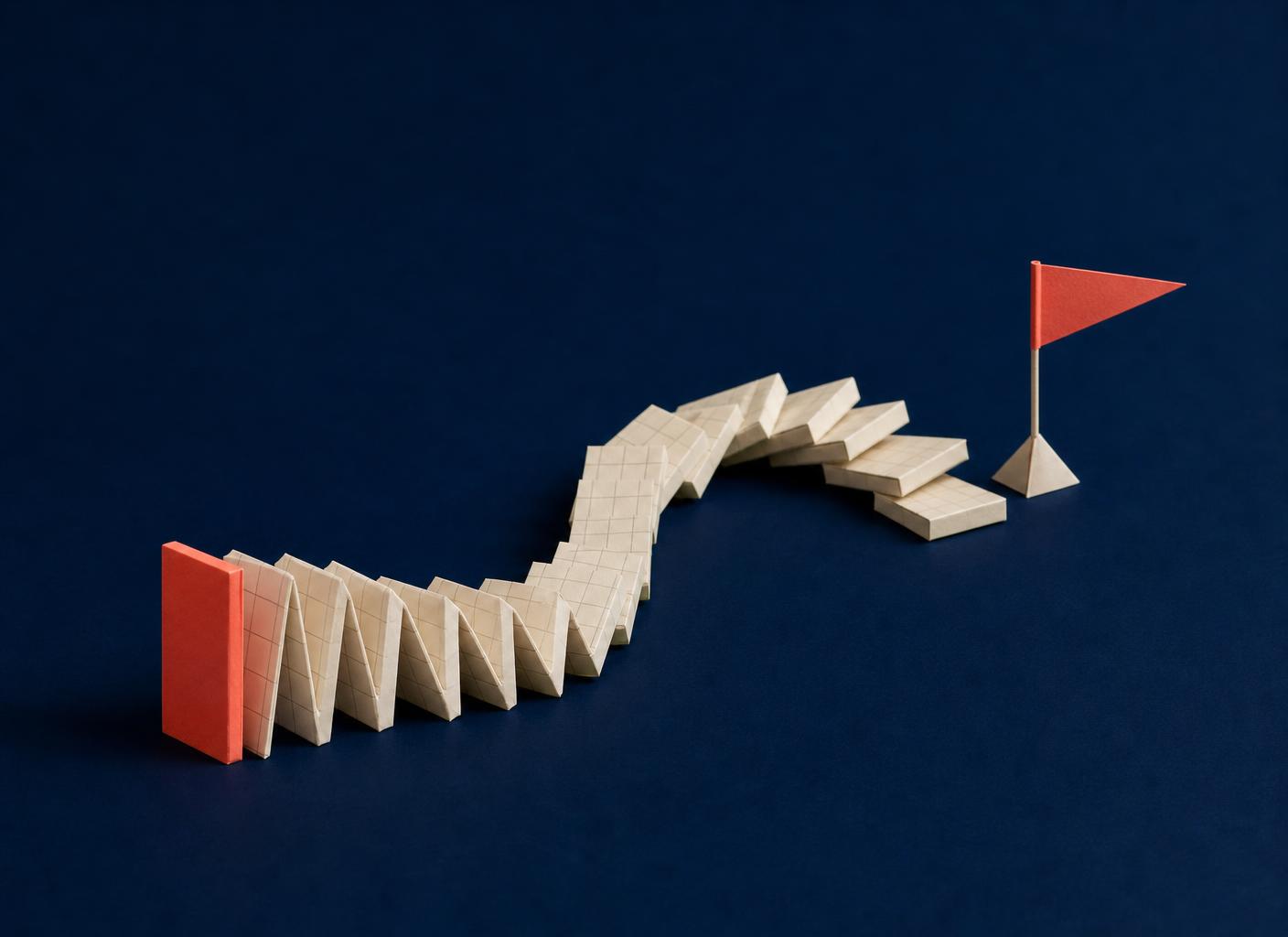 Paper-craft domino run of forms toppled by a single coral tile toward a coral flag